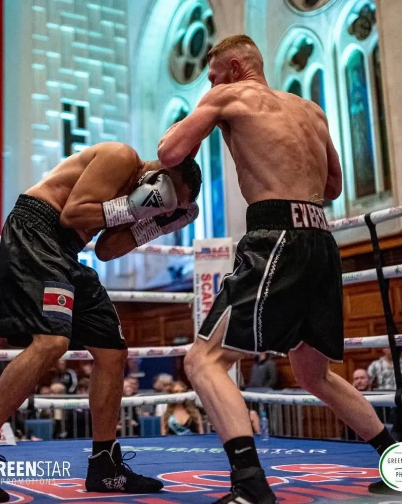 Lewis Everson in EVERSON shorts pressing forward with a right hand
