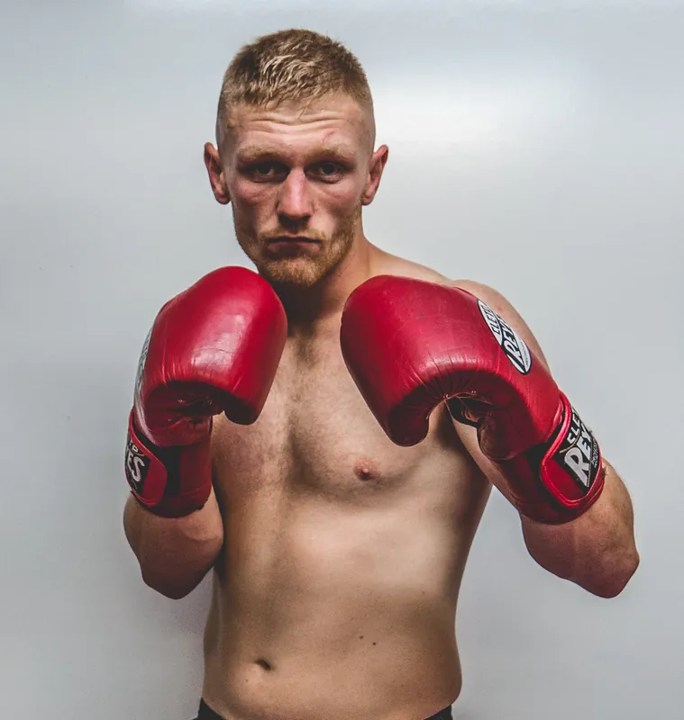 Lewis Everson in a studio portrait with red gloves up